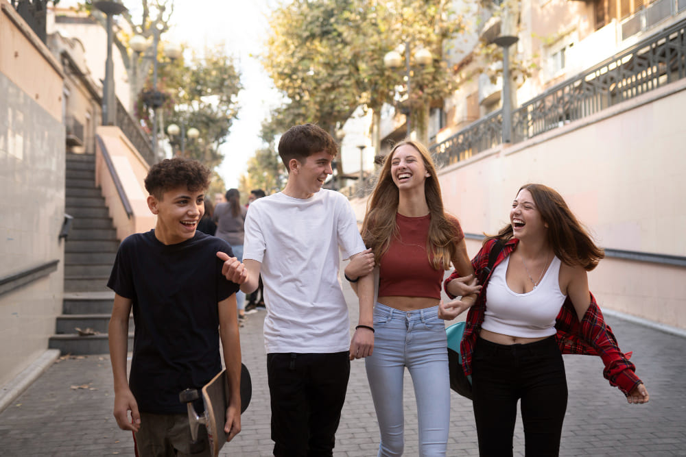 Grupo de adolescentes dos chicos y dos chicas sonriendo y hablando por la ciudad