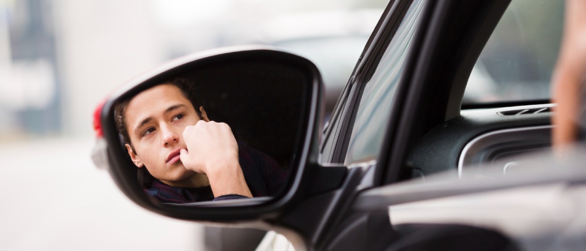 Chico joven mirando por el retrovisor preocupado