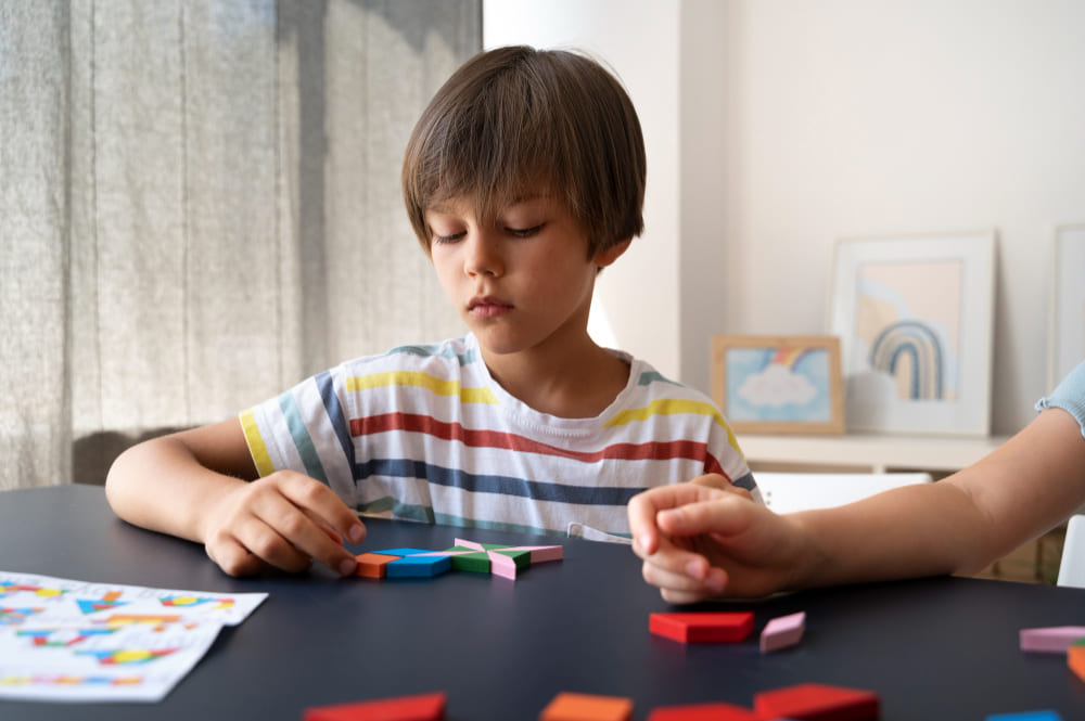 Niño pequeño concentrado con camisa de rayas mirando piezas de un puzzle