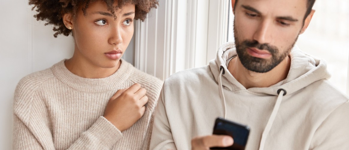 Pareja joven él mirando el móvil y ella mirando a su novio preocupados