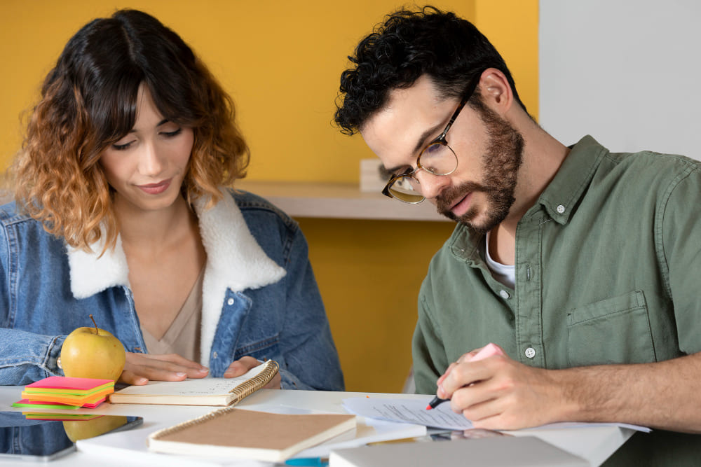Compañeros de clase, chico y chica jóvenes, escribiendo y aprendiendo durante la sesión de estudio.