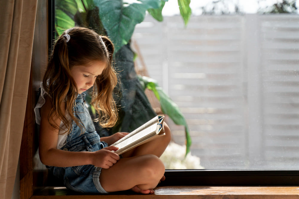 Niña pequeña leyendo un libro sentada concentrada