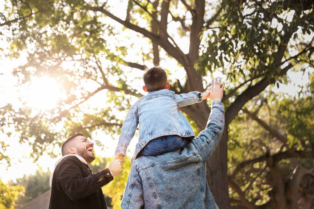 Familia feliz sonriendo en medio en la naturaleza con el niño en hombros