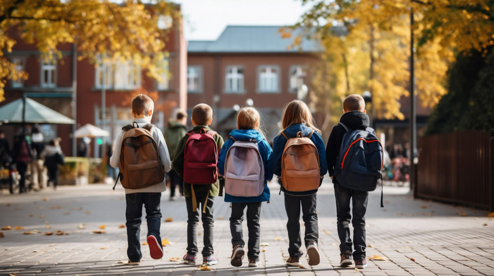 Grupo cinco niños y niñas yendo al colegio vuelta al cole día soleado
